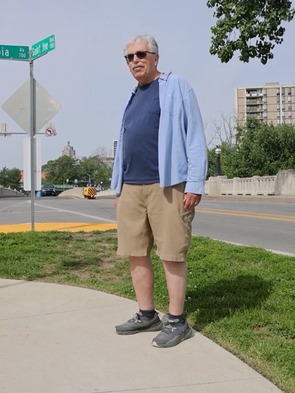 Image of Mike Roeger standing outside on the corner of a street turning and smiling at the camera.