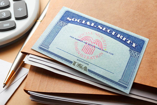 Image of Social Security card on top of a stack of folders on a desk.