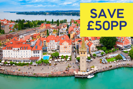 Aerial view of a picturesque lakeside town with colourful buildings and a clock tower.