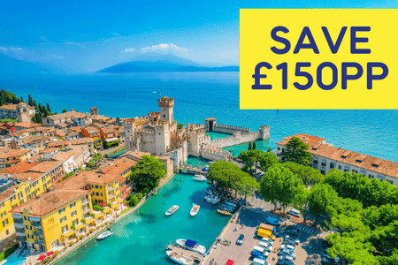 Aerial view of a picturesque lakeside town with colourful buildings and a castle by the water.