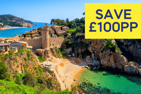 Scenic coastal view featuring a castle, sandy beach, and turquoise waters.
