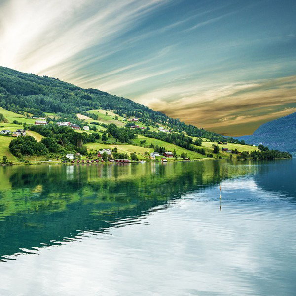 Dramatic skies over a tranquil fjord in Norway.