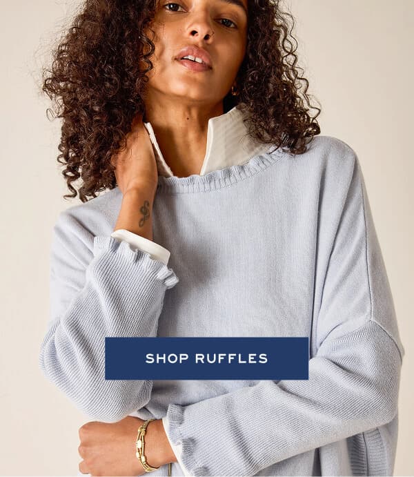 Shop ruffles - Image of a woman wearing a light blue sweater with ruffle details 