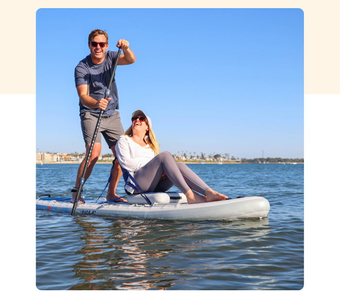 2 individuals sitting on a paddleboard