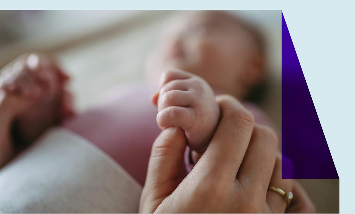 A close-up of a mother holding a baby girl's hand. 
