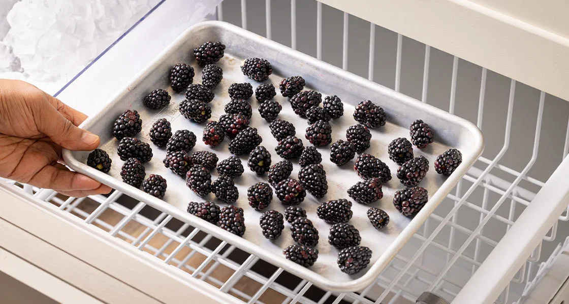 Placing berries on a sheet pan into the freezer