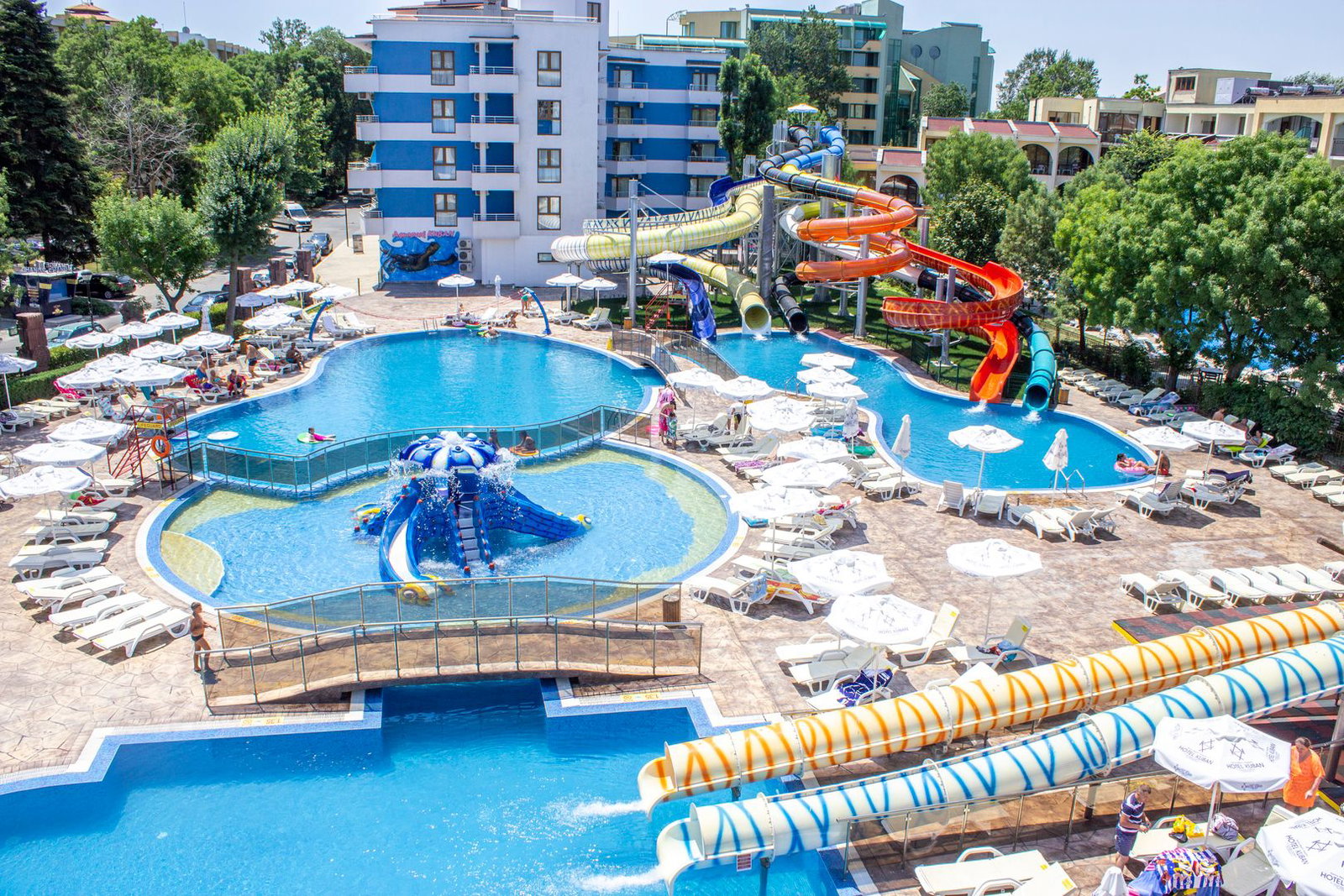 Aerial view of a hotel waterpark with colourful twisting waterslides, multiple pools, sunloungers and umbrellas