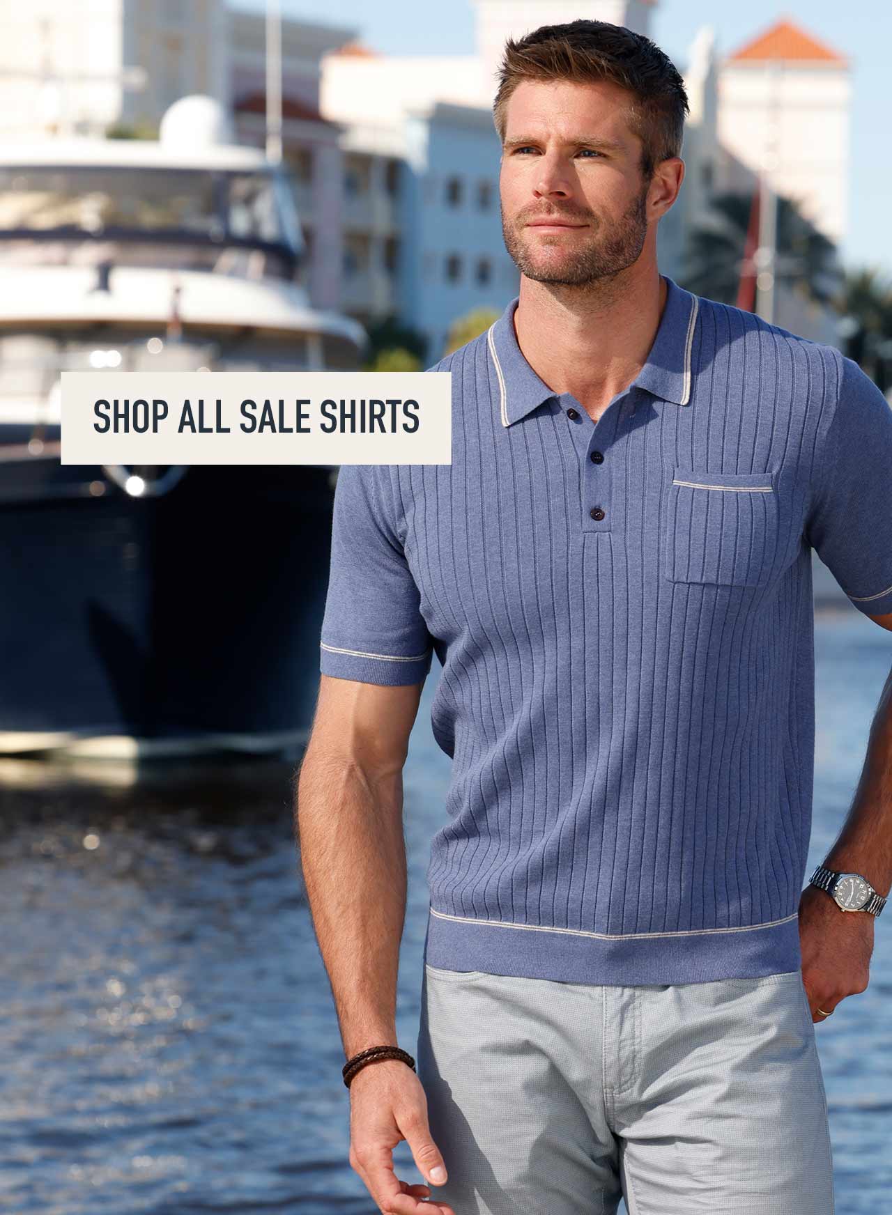 Model at a marina wearing a sage green cable-knit button-up shirt. Shop All Sale Shirts.