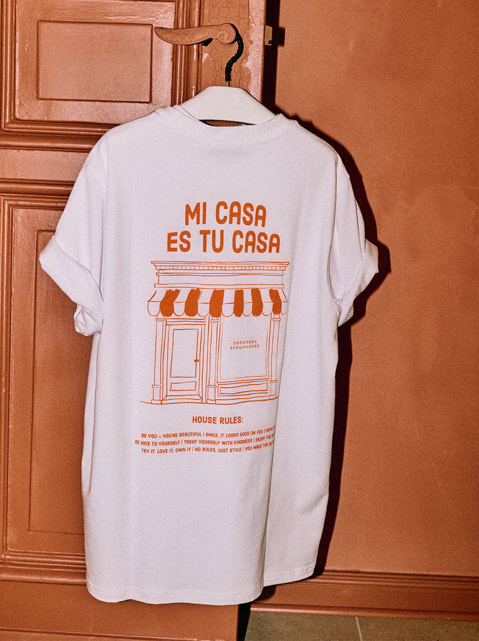 Animiertes GIF mit Stillleben der Dorothee Schumacher SS26 Kollektion: ein weißes T-Shirt mit großformatigem Blumenprint in Blau und Braun auf Stein, ein sandfarbener Mantel mit Revers im Sonnenlicht, zwei bedruckte Papierschiffe auf türkisfarbenem Wasser, ein hellgrauer Strickpullover mit floralen Stickereien und sichtbarem Dorothee Schumacher Label sowie ein üppiges Blumenarrangement in Gelb und Ocker.