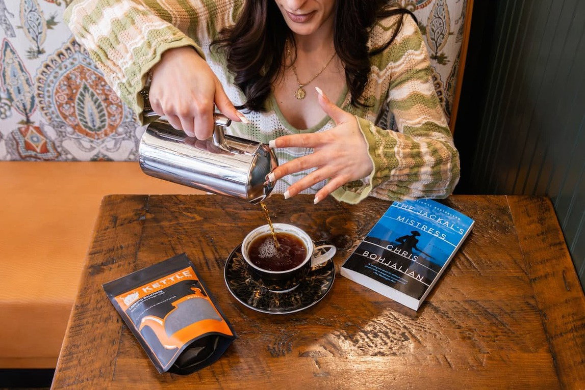 girl holding the list of supicious things book and cup of vanilla cream hot tea
