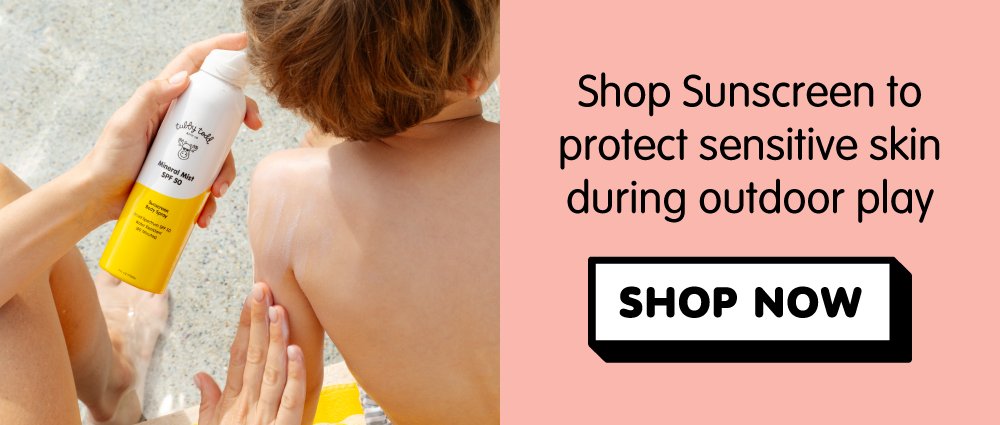 Parent sprays Tubby Todd Mineral Mist SPF 50 sunscreen onto a child's back. Shop sunscreen to protect sensitive skin during outdoor play.