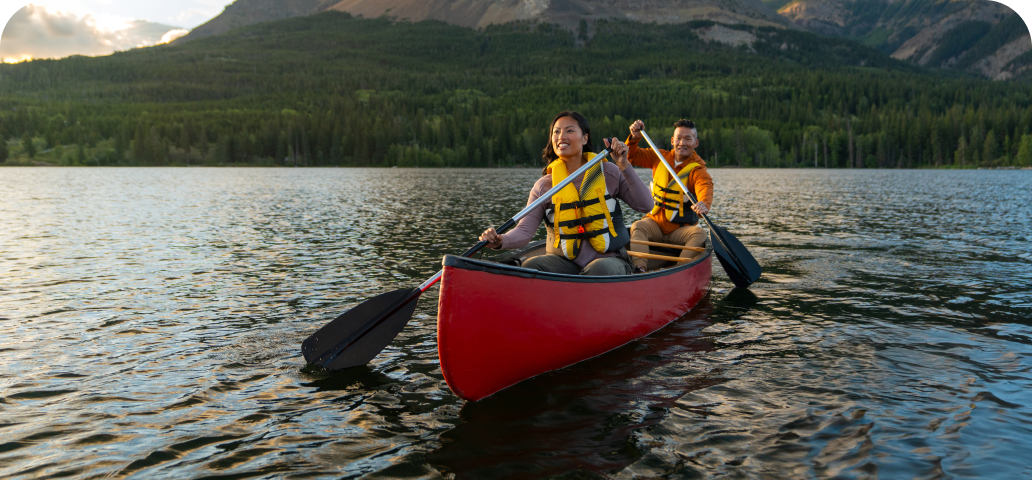 Two people canoeing on a calm lake surrounded by Canadian wilderness