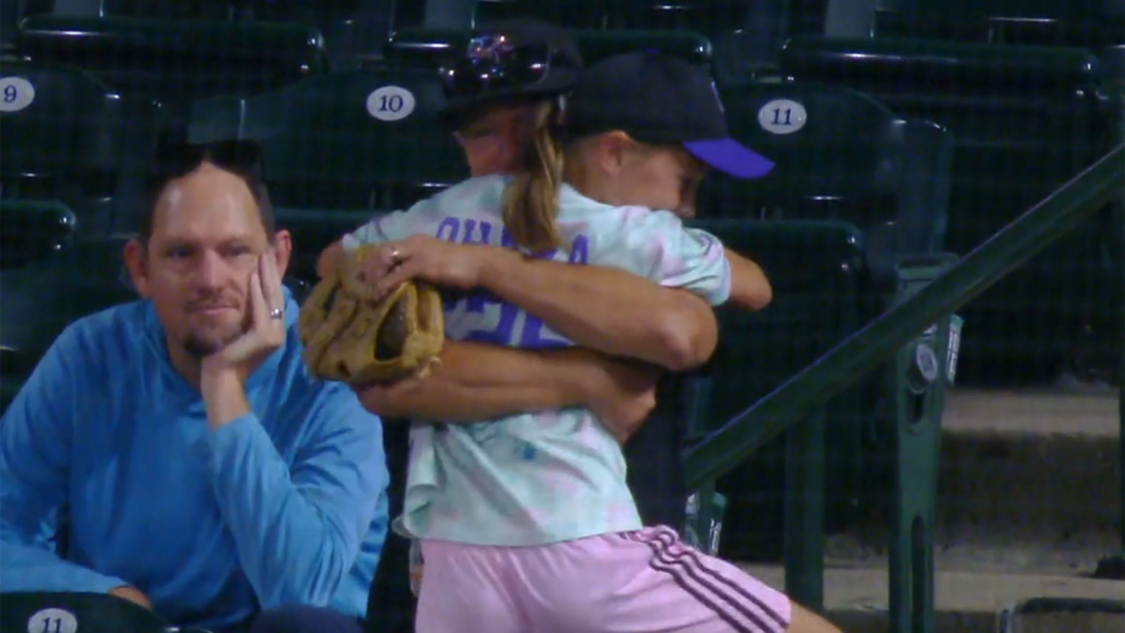 A young girl in an embrace after getting a baseball