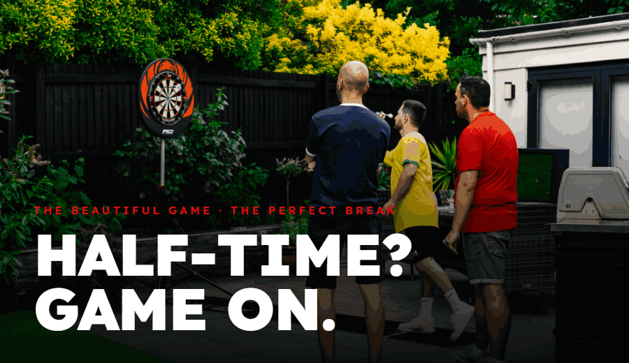 Half-time? Game on. Three friends throwing darts at a Red Dragon board while watching the football in the garden