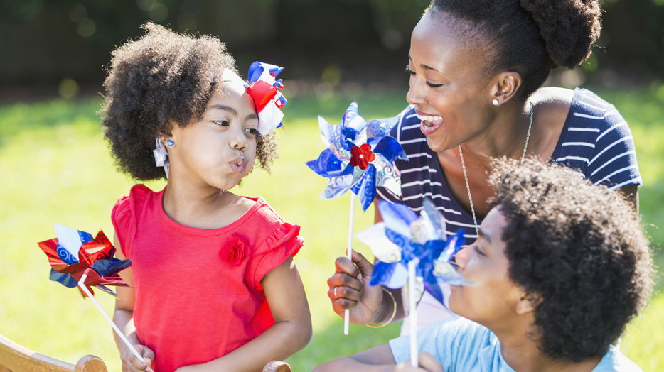 Mother and children celebrating 4th of July and playing with red, white and blue pinwheels. 