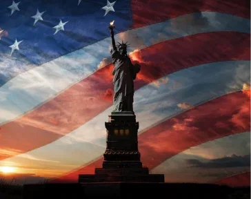 The Statue of Liberty superimposed over a sunset ad a waving American flag.