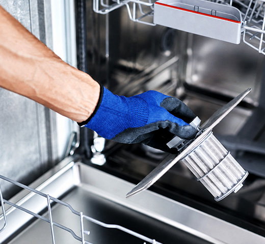 A person cleaning out the filter of a dishwasher