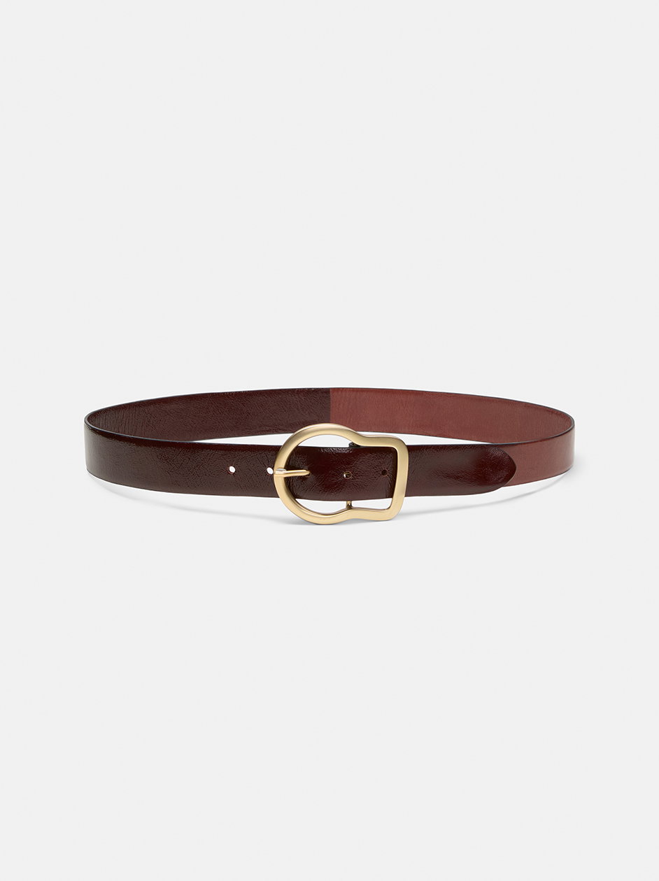 Ein edler, bordeauxroter Ledergürtel von DOROTHEE SCHUMACHER mit einer charakteristischen, asymmetrisch geschwungenen goldenen Schnalle.