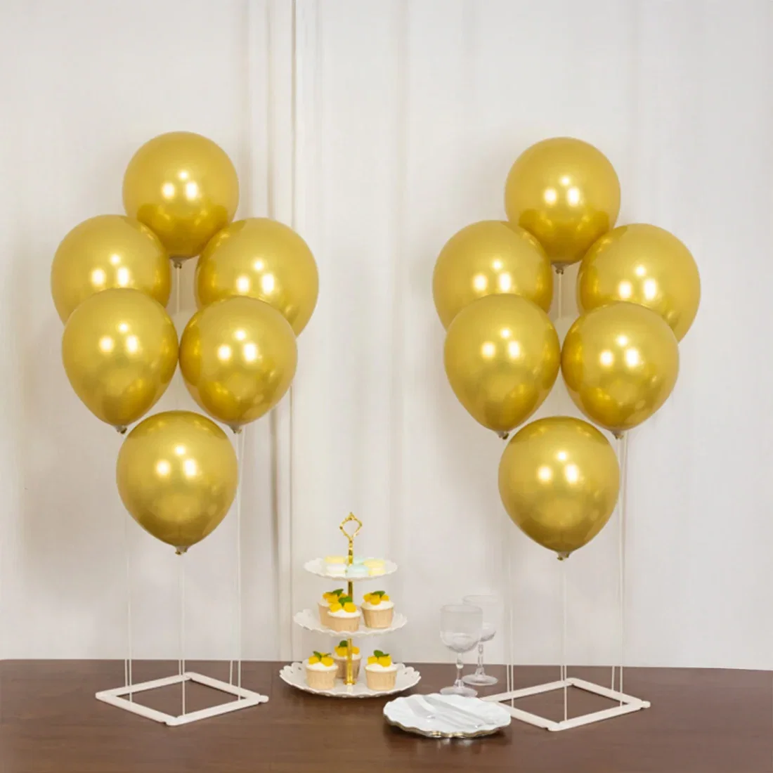 Gold balloon columns on white stands with party table decor