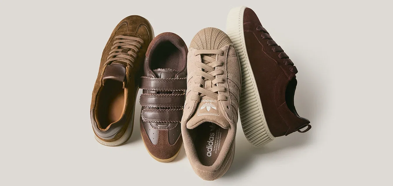 Vier paar sneakers: bruin suede, donkerbruin leer met strepen, beige canvas met een gestructureerde neus, en bordeauxsuede met een gegroefde zool.