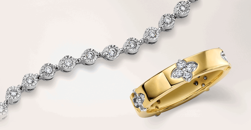 A silver tennis bracelet next to a yellow gold ring with floral diamond accents. 