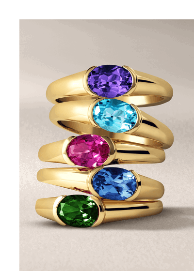 A stack of gold rings each with a different color gemstone. 