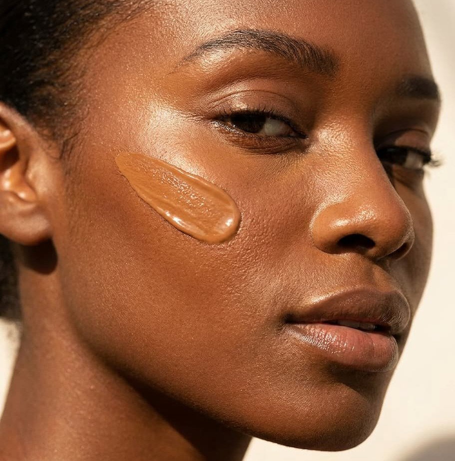 Black woman with tinted moisturizer on her cheekbone in sun. 