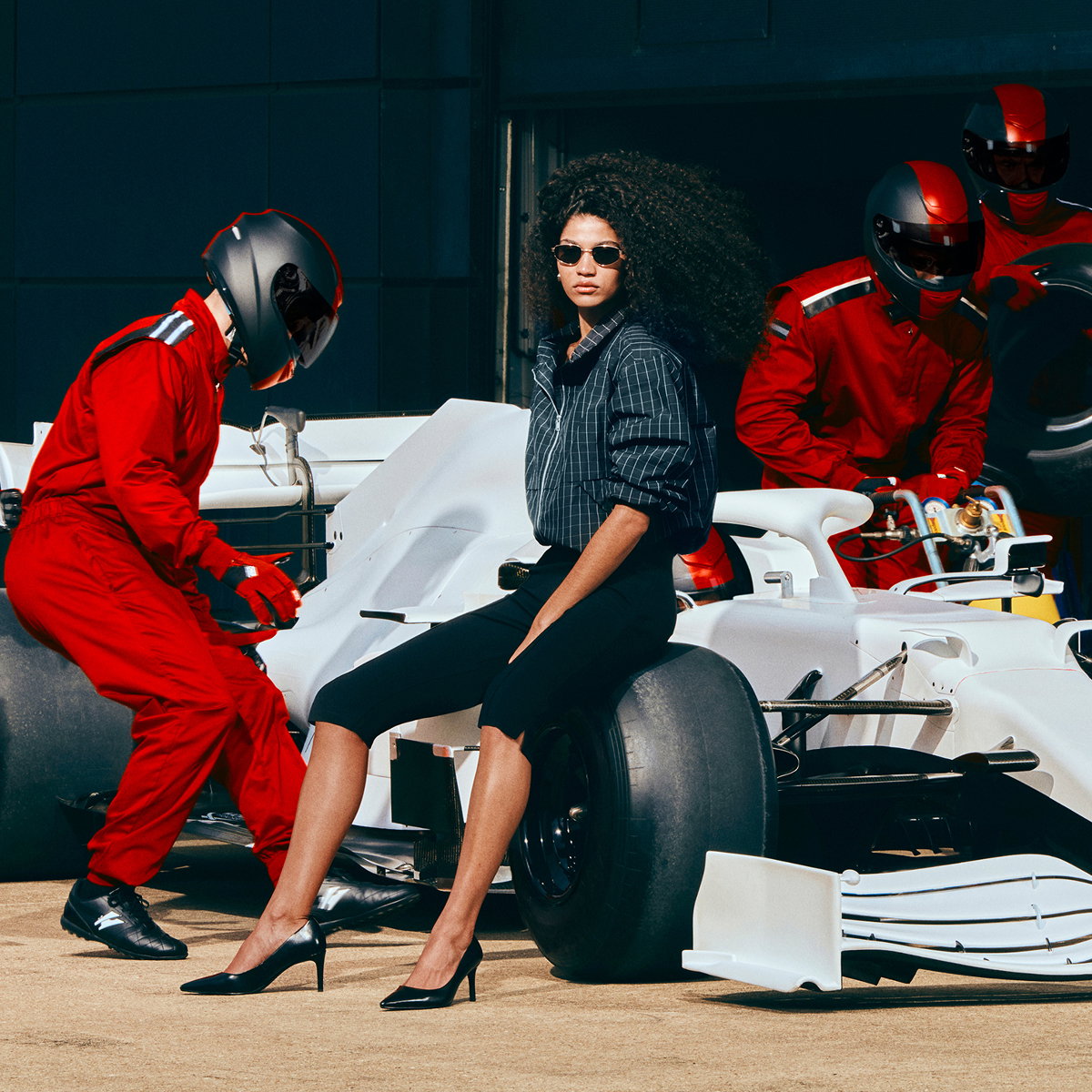 Woman, sitting on a racecar, wearing a black Checked Funnel Neck Windbreaker Jacket