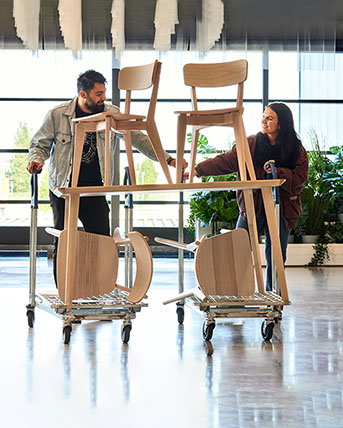 Customers rolling IKEA chairs on a flat cart.