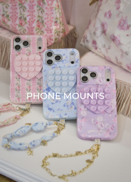 Three phones dressed in the Case-Mate x LoveShackFancy phones cases and matching accessories.