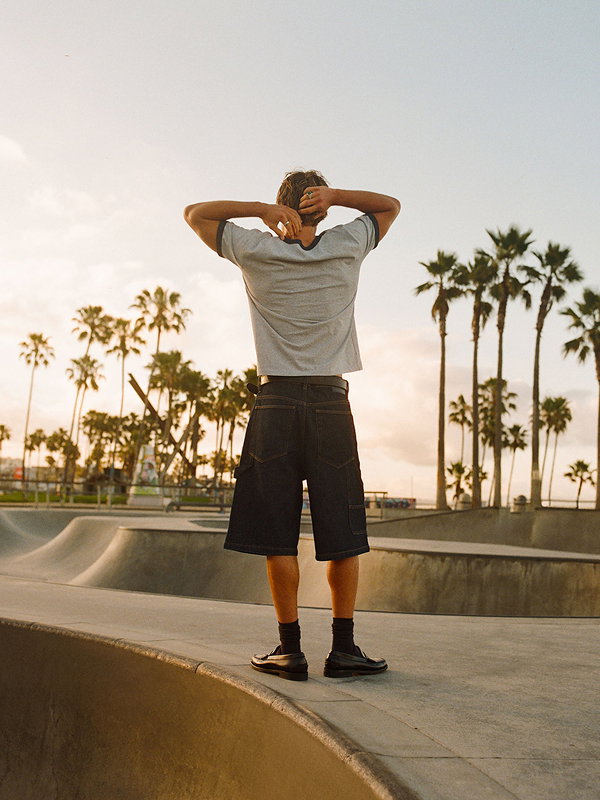 Man wearing gray t-shirt and black shorts at skate park