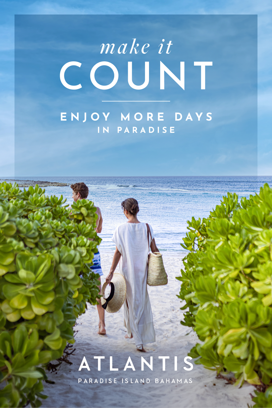 Make It Count: Enjoy more days in Paradise at Atlantis Bahamas. | A couple walking between lush green bushes toward a pristine white sand beach and turquoise ocean water.