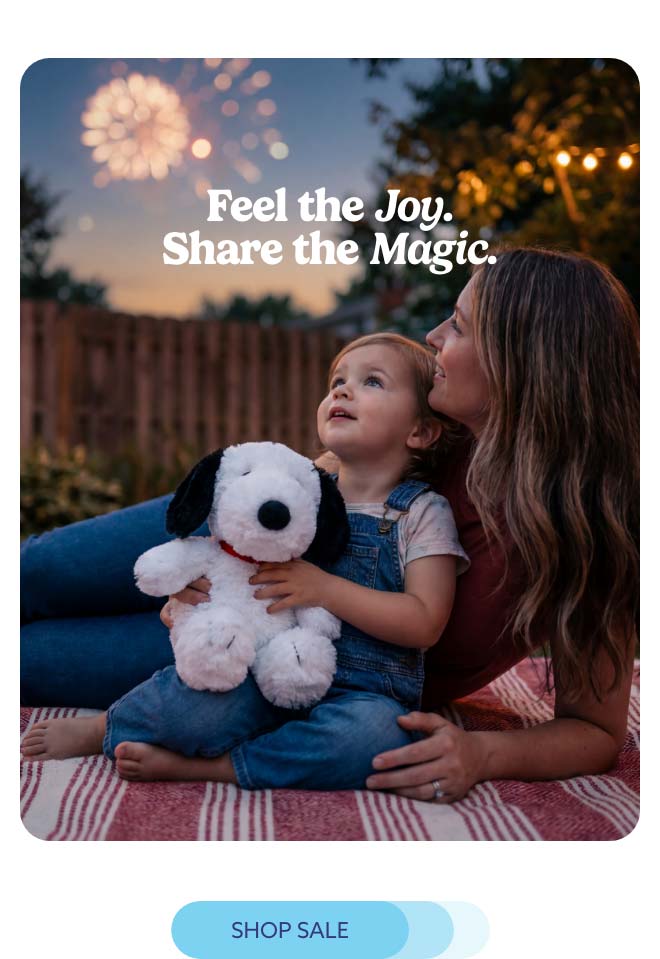 A little girl hugging Snoopy Warmies under fireworks. Shop Sale.