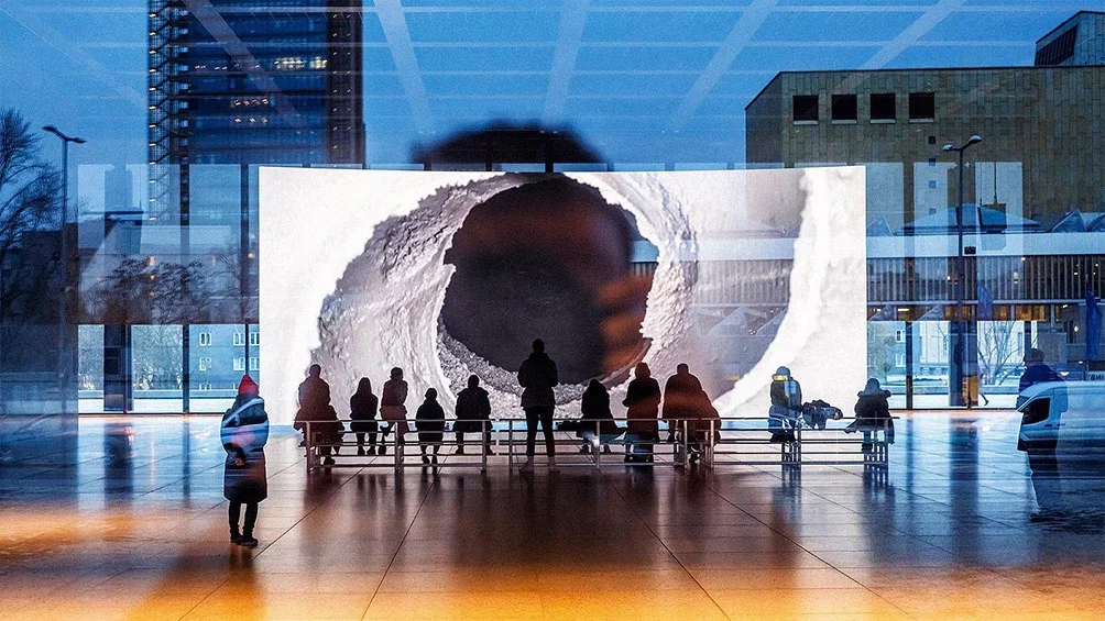 Image description: People viewing art exhibit, in the evening, at Neue Nationalgalerie, in Berlin.
