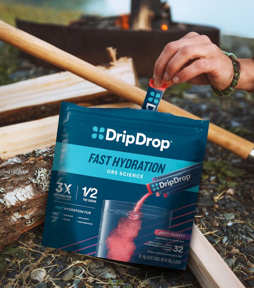 Person reaching for a DripDrop stick at a campfire