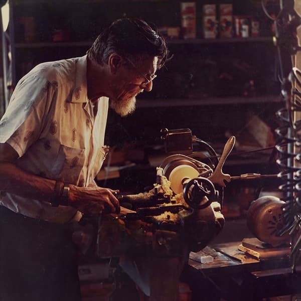 Paul W. Klipsch using a wood carver, in a dimly light workshop