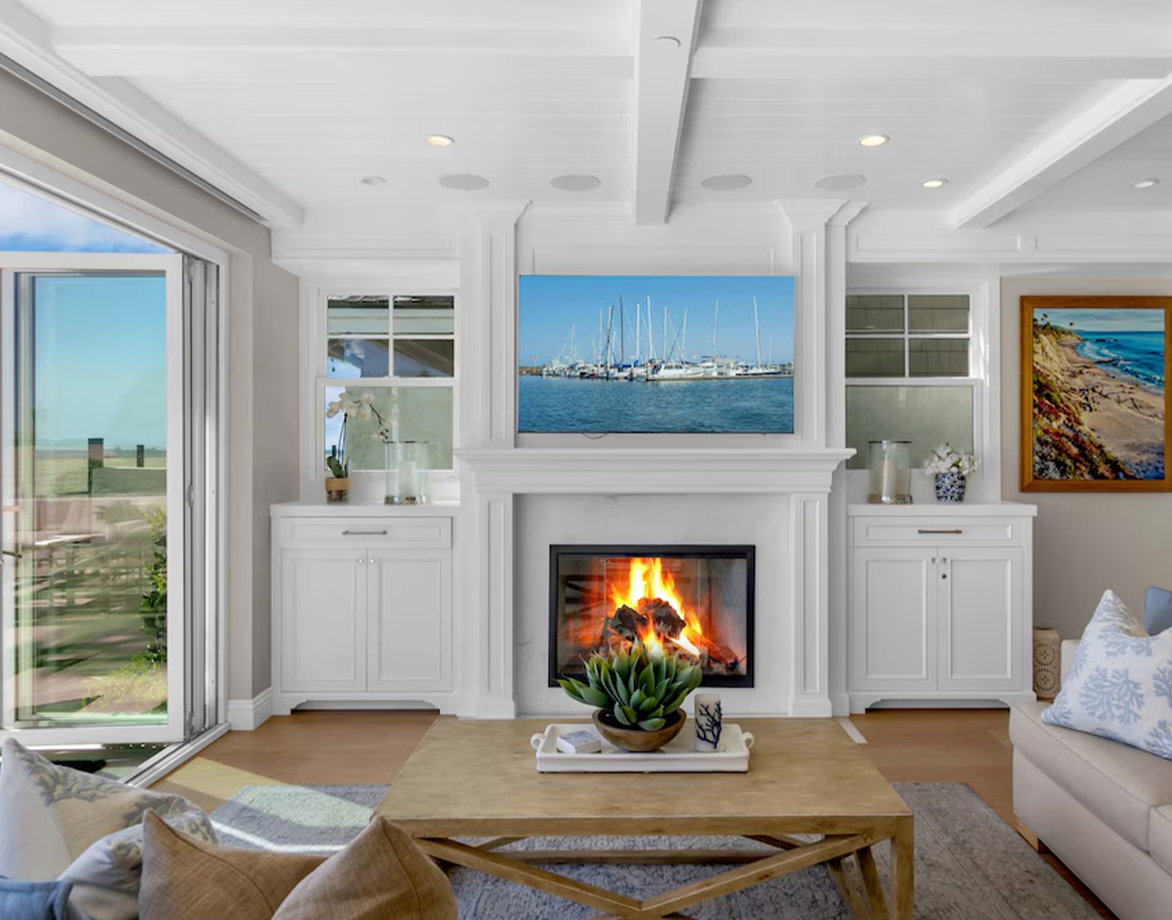 Bright living room with white fireplace, photo frames above the mantel, and a wood table.