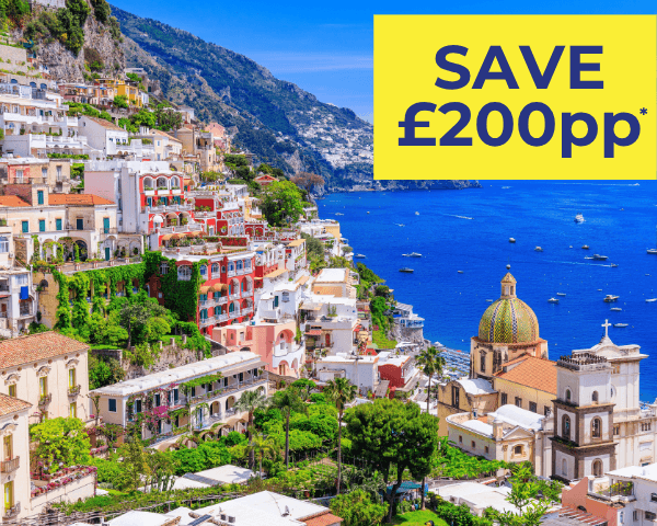 Scenic view of colourful coastal buildings in Positano, Italy, with a blue sea and mountains.