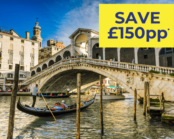 A gondola glides through the Grand Canal, with the Rialto Bridge in the background.