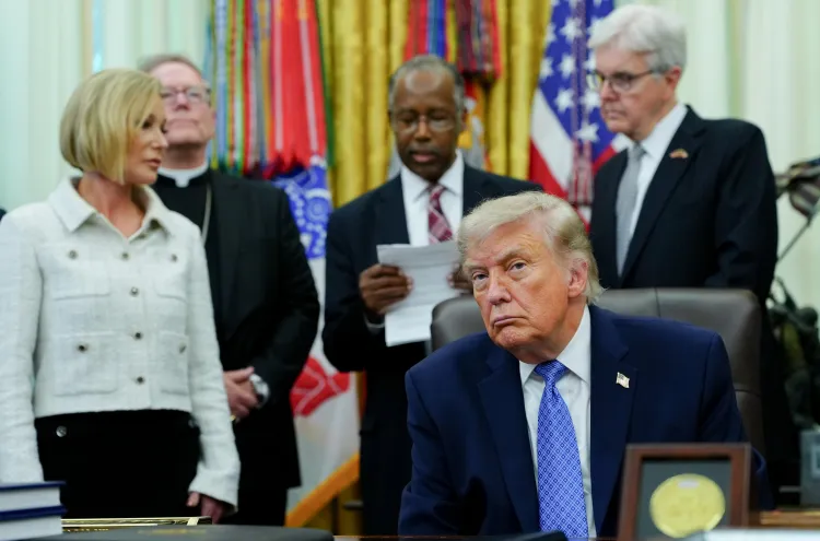 Trump, in the Oval Office, is flanked by religious leaders reading from a document.