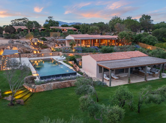 A large villa with an outdoor living space and a pool.
