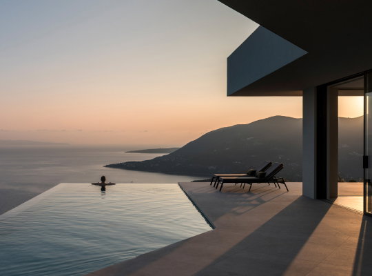 A villa with a deck and pool overlooking the sea.