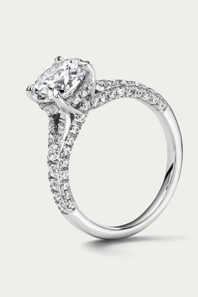 A white metal ring with a round cut center stone and diamonds along the shank.