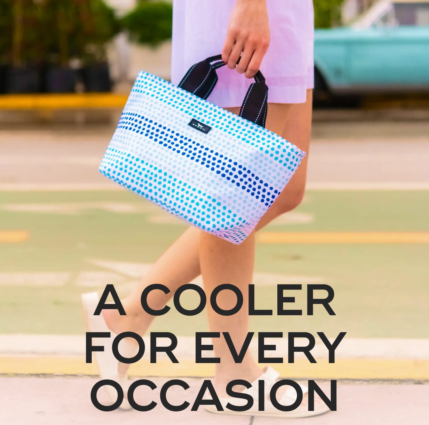 A COOLER FOR EVERY OCCASION. Woman carrying a blue and white polka dot SCOUT cooler bag.