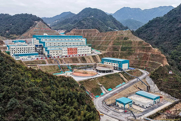 A vast lithium mine is set into a landscape of forested hills.