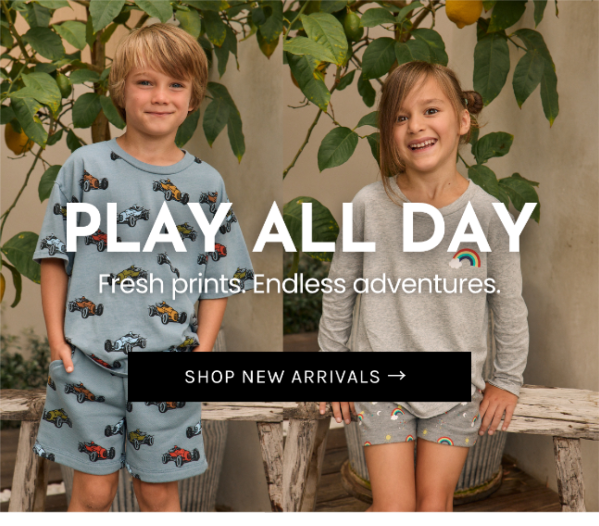Children modeling Chaser Kids Summer Delivery 03 styles featuring vintage race car prints, rainbow graphics and retro-inspired lounge sets, photographed outdoors beneath a lemon tree on a warm summer day.