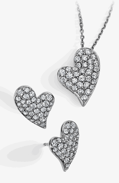 A heart-shaped multi-diamond necklace next to a pair of matching earrings.