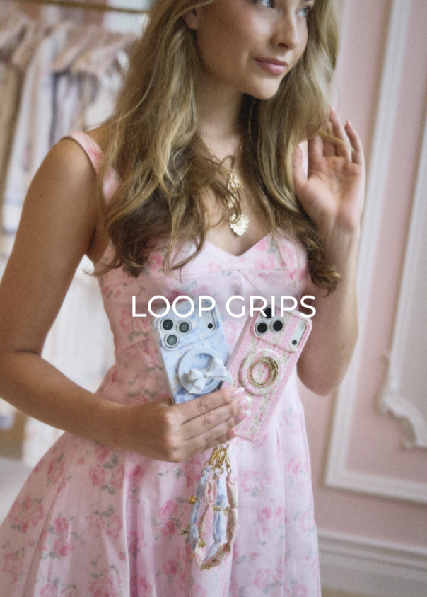 A girl holding up two phones that have Case-Mate x LoveShackFancy phone cases and matching accessories.