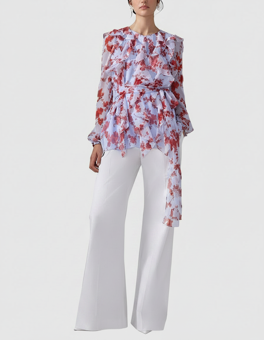 Woman in a floral ruffled blouse and white wide-leg pants.