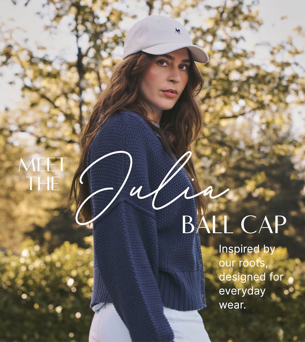 Model in white Julia Ball Cap, navy cardigan, and white pants. Text: “Meet the Julia Ball Cap.”